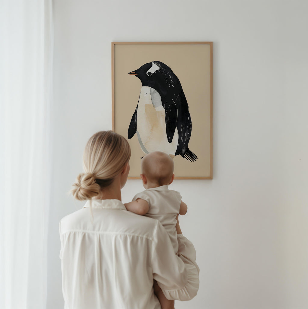 Woman holding a baby looking at a framed penguin artwork on a wall.